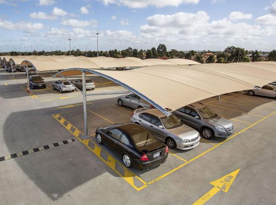Car parking shade structure providing UV protection and weather coverage for vehicles in a commercial parking lot